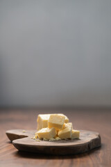 White cheddar cheese pieces on olive wood board
