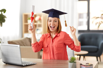 e-learning, education and people concept - happy smiling female graduate student in mortarboard...