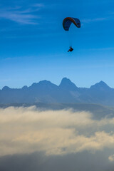 Man paragliding above the clouds