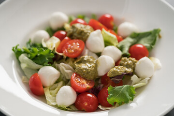 Salad with miced greens , tomatoes and mozzarella in white bowl