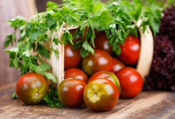 Fresh homemade tomatoes with parsley leaves on wooden table.
