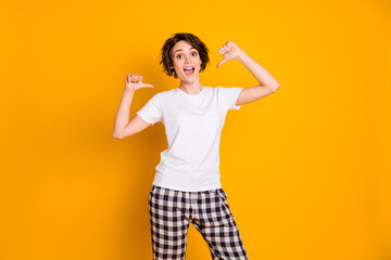 Photo of pretty lady hold hands direct fingers herself weekend morning quarantine stay home wear white t-shirt plaid pajama pants isolated yellow color background