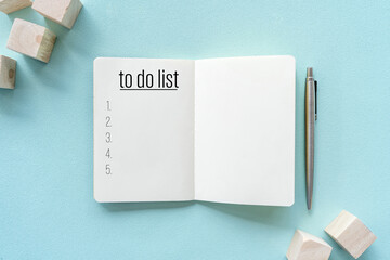 Notebook and pen with to do list words on pastel color background.