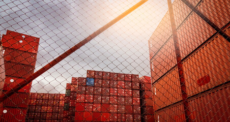 View from fence of red container stacked. Container logistics. Cargo and shipping. Import and...