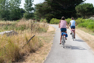 two girls ride bike in path bikeway in Ile de noirmoutier island in France Vendée