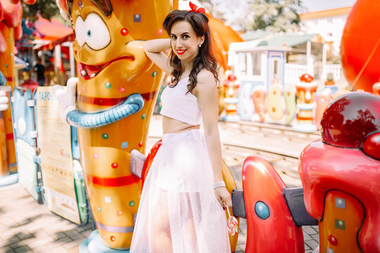 Beautiful brunette girl in and the amusement park with candy caramel in retro pin-up style