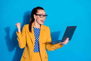 Portrait of her she nice attractive pretty chic satisfied cheerful cheery glad lady holding in hands laptop rejoicing winning tender isolated bright vivid shine vibrant blue color background