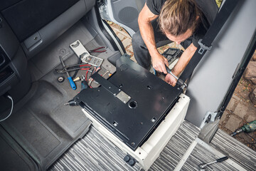 Man installing a swivel seat base in his camper van