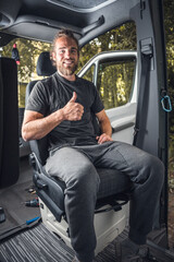 Happy man sitting in a swivel seat inside his van
