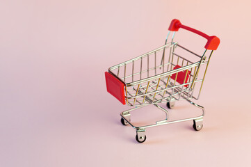 The image of empty shopping trolley or cart on pink background