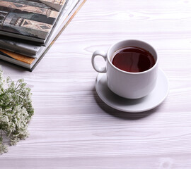 a white ceramic cup with black tea and diffrent objects on the light background
