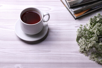a white ceramic cup with black tea and diffrent objects on the light background