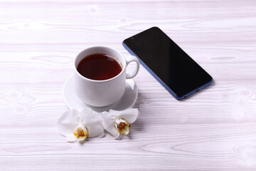 a white ceramic tea cup and different objects on the light wooden surface