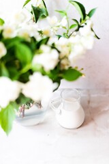 Obraz na płótnie Canvas Fresh milk in a jug in the company of flowers