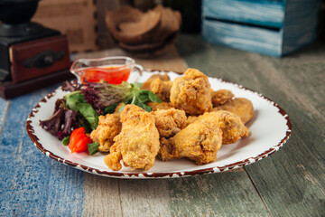 Crispy deep-fried chicken wings with greens 