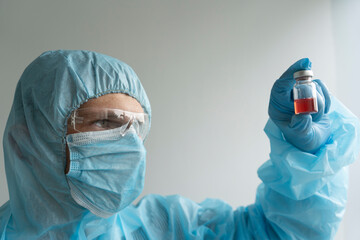 Drug development process, a doctor in a protective suit holds an ampoule