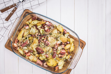 Baked octopus with potato and olives on white table, top view