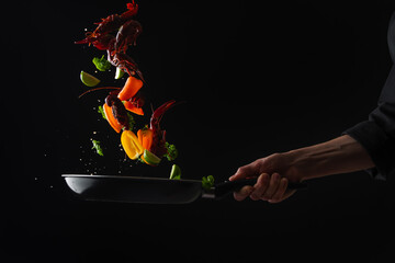 Cooking seafood, frying in a pan with vegetables, veggie healthy food, on a black background, menu and restaurant business - obrazy, fototapety, plakaty