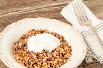traditional buckwheat porridge served with yoghurt on a wooden table