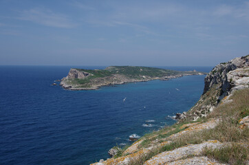 Fototapeta na wymiar A ridge of the island of San Nicola that falls overhanging the sea and in the background the island of Capraia with its abandoned lighthouse - Tremiti Islands - Adriatic Sea - Italy