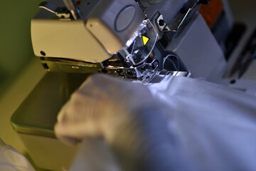 seamstress works on a sewing machine in protective gloves late in the evening
