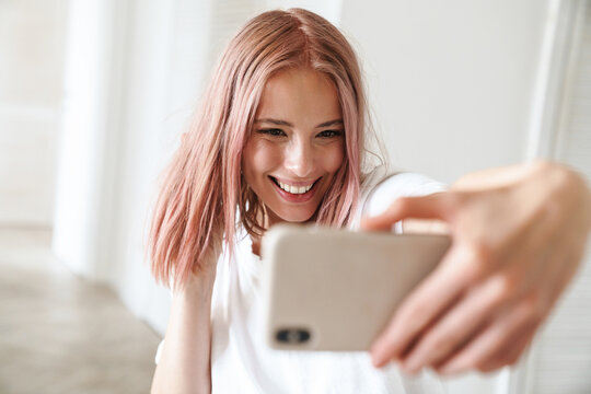 Photo of caucasian excited woman taking selfie photo on mobile phone