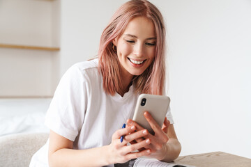 Image of woman using smartphone while doing homework with exercise books