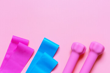 Elastic expanders and pink dumbbells on pink background copy space
