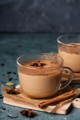 Glass cups of traditional Indian masala chai on dark green texture background. Ingredients of beverage black tea, ginger, cinnamon, cardamom, anise stars