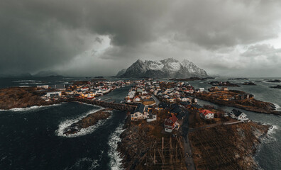 Henningsvaer aerial panorama shoot at winter. Outstanding sky and snowy mountain peak on horizon and village buildings along harbor. Lofoten Islands, Norway.
