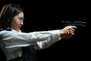 Woman wearing bulletproof vest shoots with gun at a target at indoor gun range. © marchsirawit