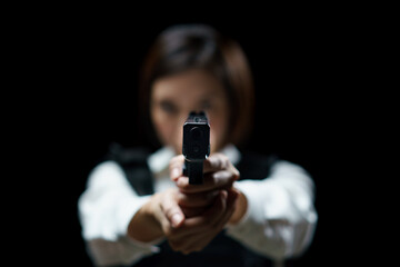 Woman wearing bulletproof vest shoots with gun at a target at indoor gun range.