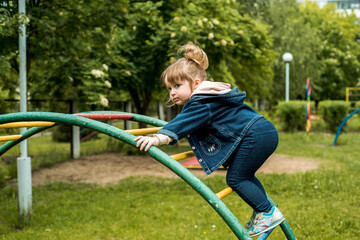 little girl on the playground. Happy smiling child playing on outdoor.Baby laughs, shouts emotionally, joy and a happy childhood.