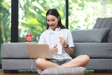 Asian woman student sitting at floor in living room, using computer laptop and presenting when studying online course