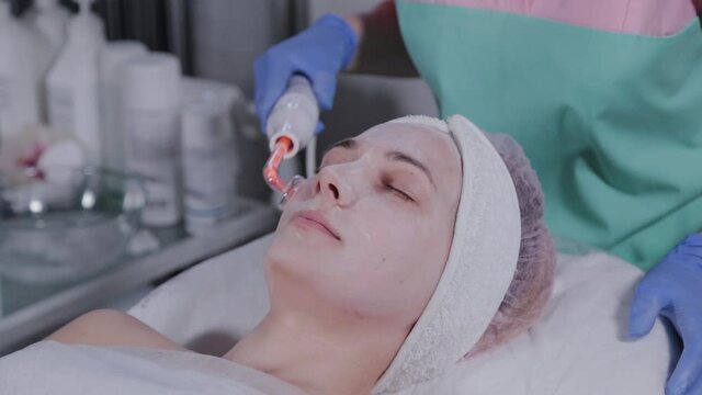 Receiving electric darsonval facial massage procedure.