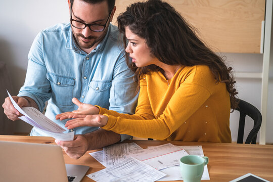 Worried unhappy couple arguing about debt or high domestic bills with laptop and documents stock photo