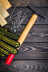 The hammer and nails for the repair of carpentry are left by the master on black wooden boards