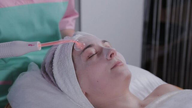 Receiving electric darsonval facial massage procedure.