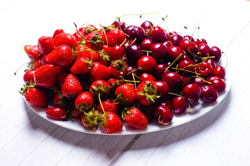 Ripe cherries and strawberries on a white dish