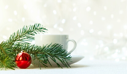 Obraz na płótnie Canvas white coffee Cup on a saucer on a white background with a garland. Near the branch of a spruce and a red ball. The concept of Christmas