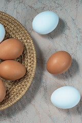 several fresh chicken eggs in a straw basket on a wooden background. Healthy eating concept.