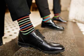 Men's feet in a row of shoes. Colored socks.