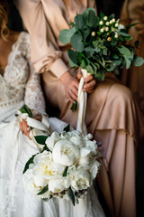 The bride holds a bouquet in her hands. Sit.