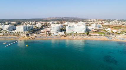 Naklejka na ściany i meble Aerial bird's eye view of Sunrise beach Fig tree, Protaras, Paralimni, Famagusta, Cyprus.The famous tourist attraction family bay with golden sand, boats, sunbeds, restaurants, water sports from above