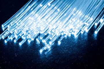 Bundle of optical fibers with lights in the ends. Blue background.
