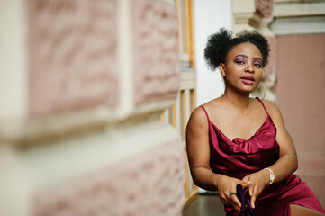 Portrait of a beautiful natural young African woman with afro hair. Black model in red silk dress.