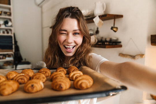 Cheerful young girl taking a selfie and showing baked cookies