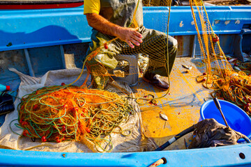 Fisherman is empty fish from net in his small boat