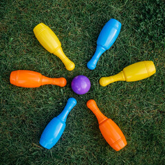 Children's set to play bowling on green grass. Ball and colored pins. Kid's game toy. Bowling colorful plastic pins. Active and interesting childhood concept.
