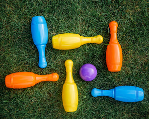 Children's set to play bowling on green grass. Ball and colored pins. Kid's game toy. Bowling colorful plastic pins. Active and interesting childhood concept.
